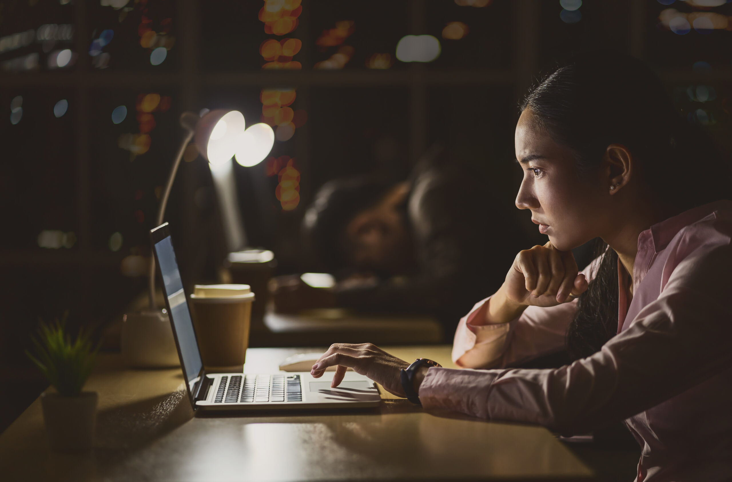 Businesswoman working with her laptop in office, low light environment.