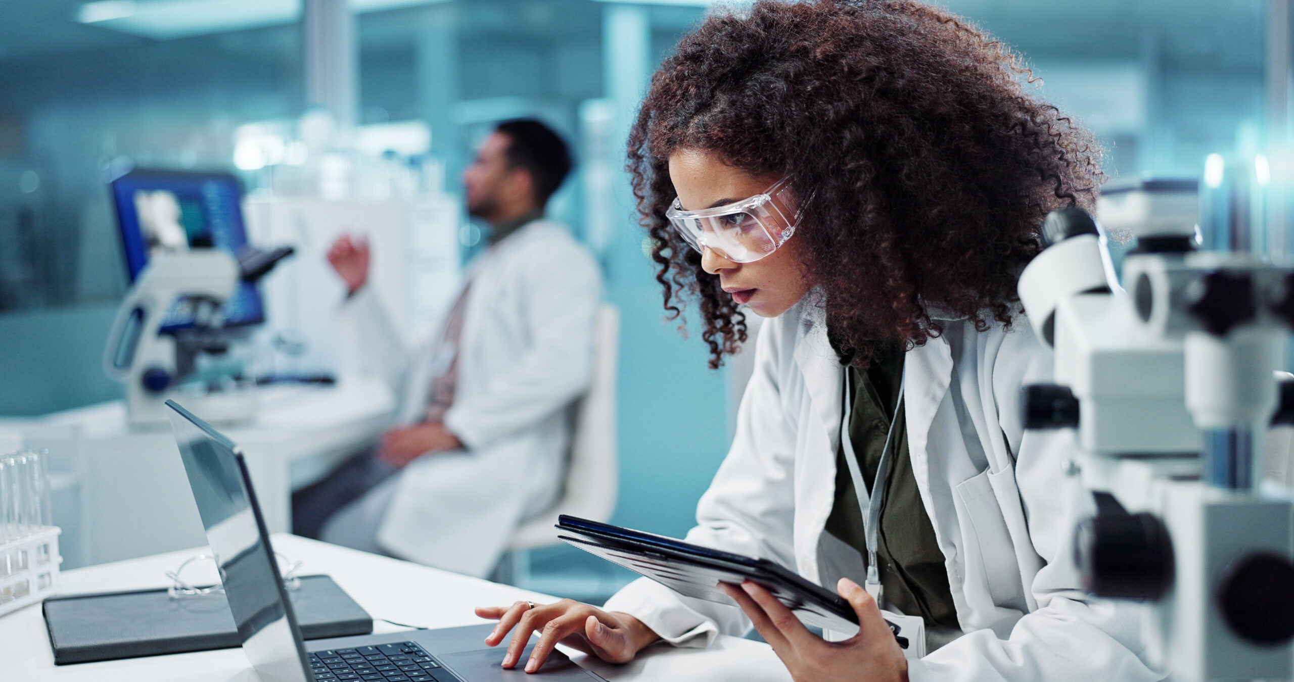 Female healthcare worker checking email on computer and using a tablet. Insider risk management and security.